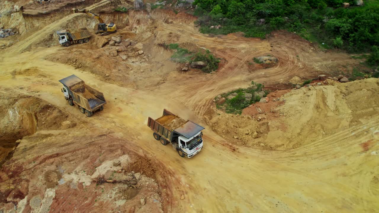 Lastbil kører frem for at læsse sand af på losseplads på byggeplads i Telangana, Indien. Dagtid, droneoptagelse. 4k.