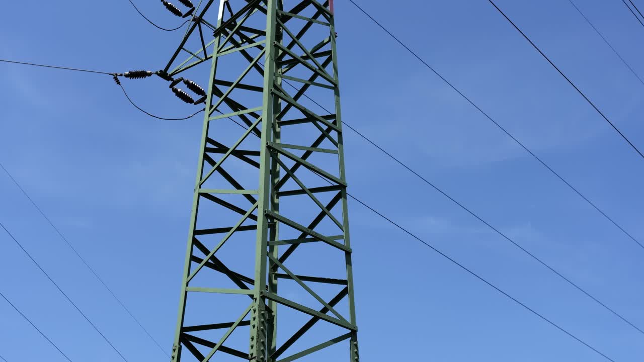 Vertikal panoreringsoptagelse, der afslører grøn elmast med højspændingsledninger til transmission af elektricitet i Europa.
