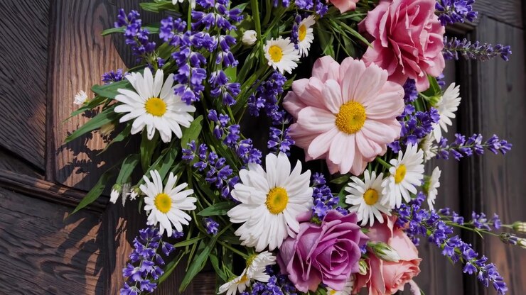 Nahaufnahme eines wunderschönen Blumenkranzes mit Gänseblümchen, Lavendel und Rosen an einer Holztür