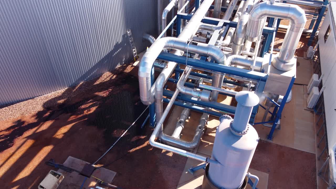 drone disparado moviéndose hacia arriba y sobre tuberías metálicas e infraestructura en una instalación industrial