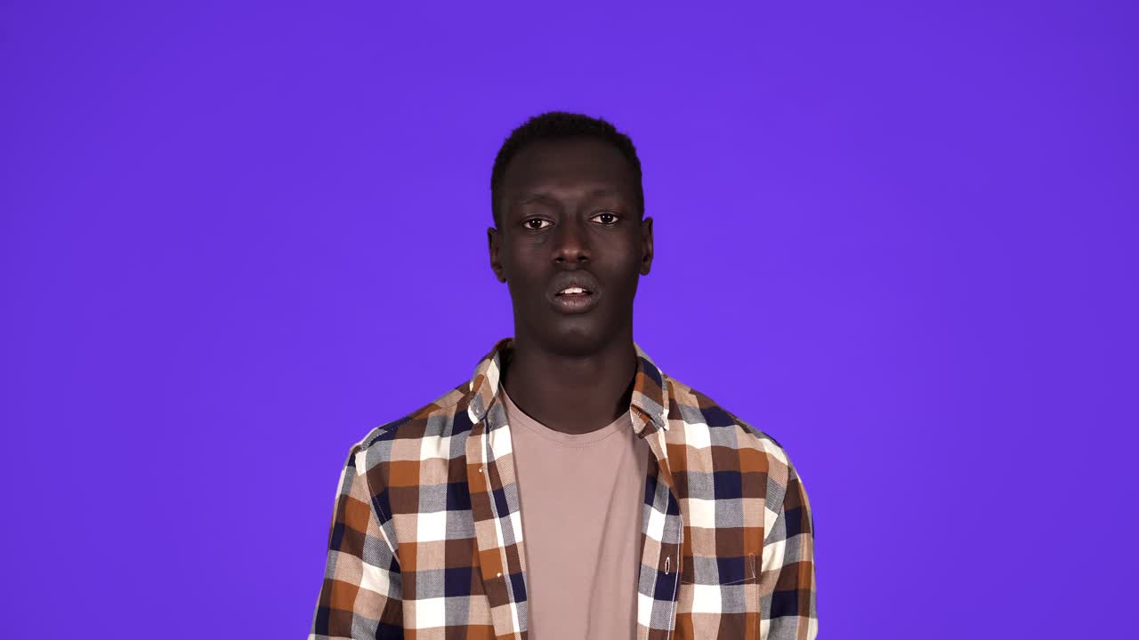 Sick young African Man coughing hard and hitting himself the chest isolated on blue background. Wearing plaid shirt