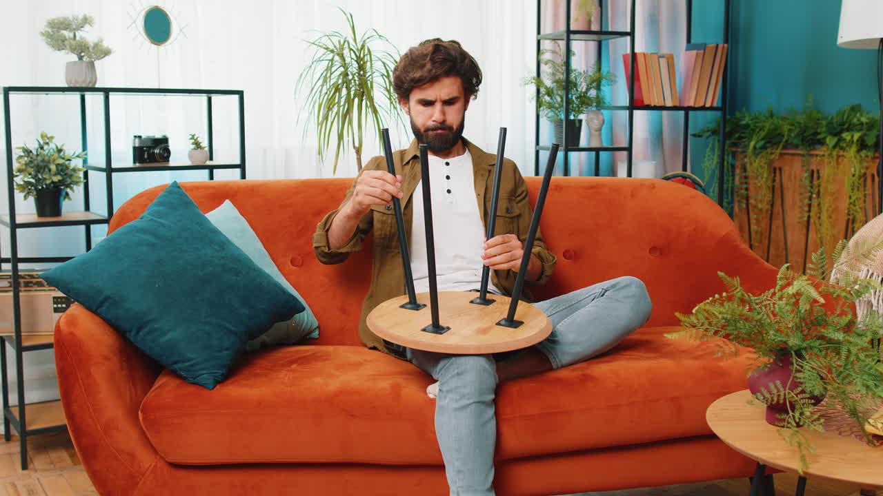 남자가 새로운 아파트에서 집에 가구를 조립하고, 성공적인 테이블을 수집하고, 수리하고, 고정합니다.