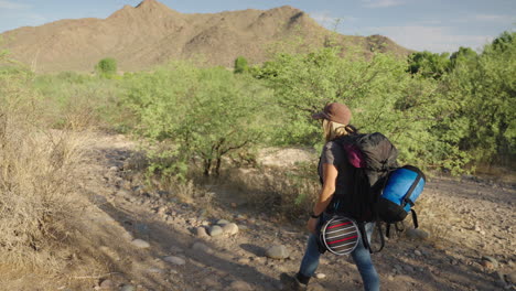 caminata por el desierto con una mujer blanca con mochila y suministros de campamento