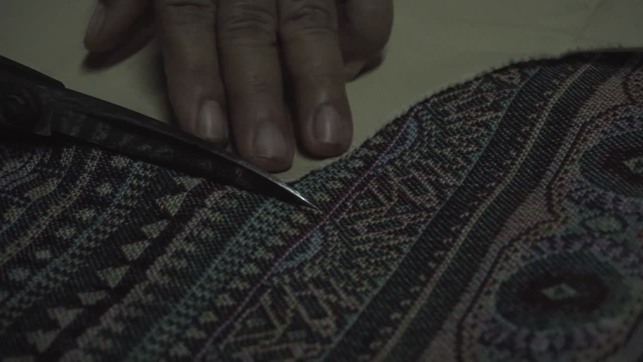 mira de cerca, la vieja sastre usa tijeras para cortar la tela tradicional tailandesa