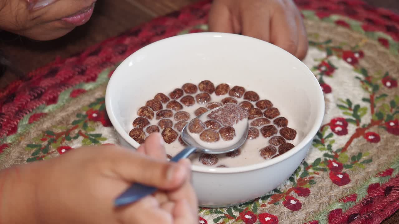 Child eating chocolate cereal with milk