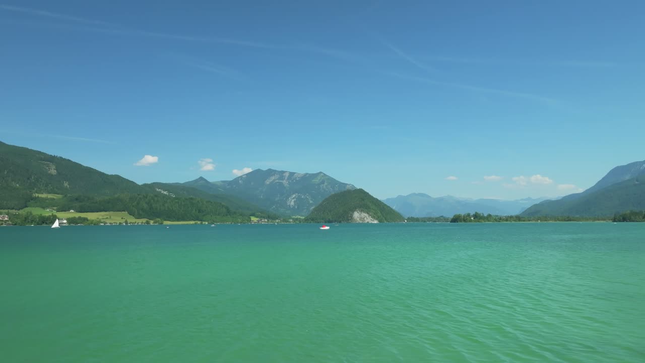 영화 속 드론은 우아하게 낮게 날아다니며 오스트리아의 화려함을 드러 ⁇ 니다. 멀리 있는 웅장한 산들로 둘러싸인 조용한 볼프강세 호수, 사탕으로  ⁇ 인 섬들로 가득 찬