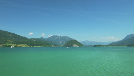 Die-Filmische-Drohne-Gleitet-Anmutig-In-Der-Tiefe-Und-Offenbart-Die-österreichische-Pracht:-Den-Ruhigen-Wolfgangsee,-Eingerahmt-Von-Majestätischen-Bergen-In-Der-Ferne,-übersät-Mit-Schilfbedeckten-Inseln