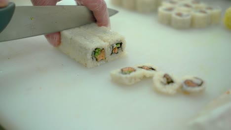 Close-up-cutting-Japanese-rolls-with-fried-fish-and-fresh-vegetables