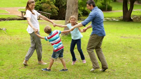 happy family playing ring a rosie in the park together