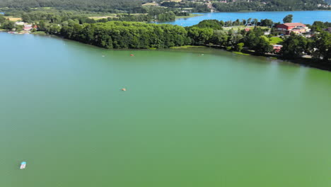 Schwenkdrohnenaufnahme-Einer-Bewohnten-Insel-Neben-Einem-Epischen-Natursee-Im-Sommer-Und-Bei-Blauem-Himmel