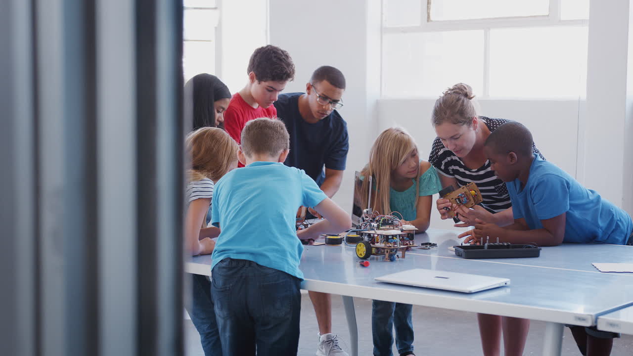 estudiantes con maestros en clases de codificación de computadoras después de la escuela aprendiendo a programar vehículos robóticos