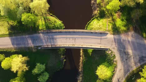 top down rising view above concrete bridge spanning small quaint river in countryside