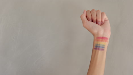 raising fist, person showing rainbow pride flag painted on wrist