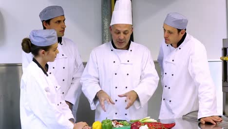 chef principal mostrando a sus aprendices cómo cortar verduras