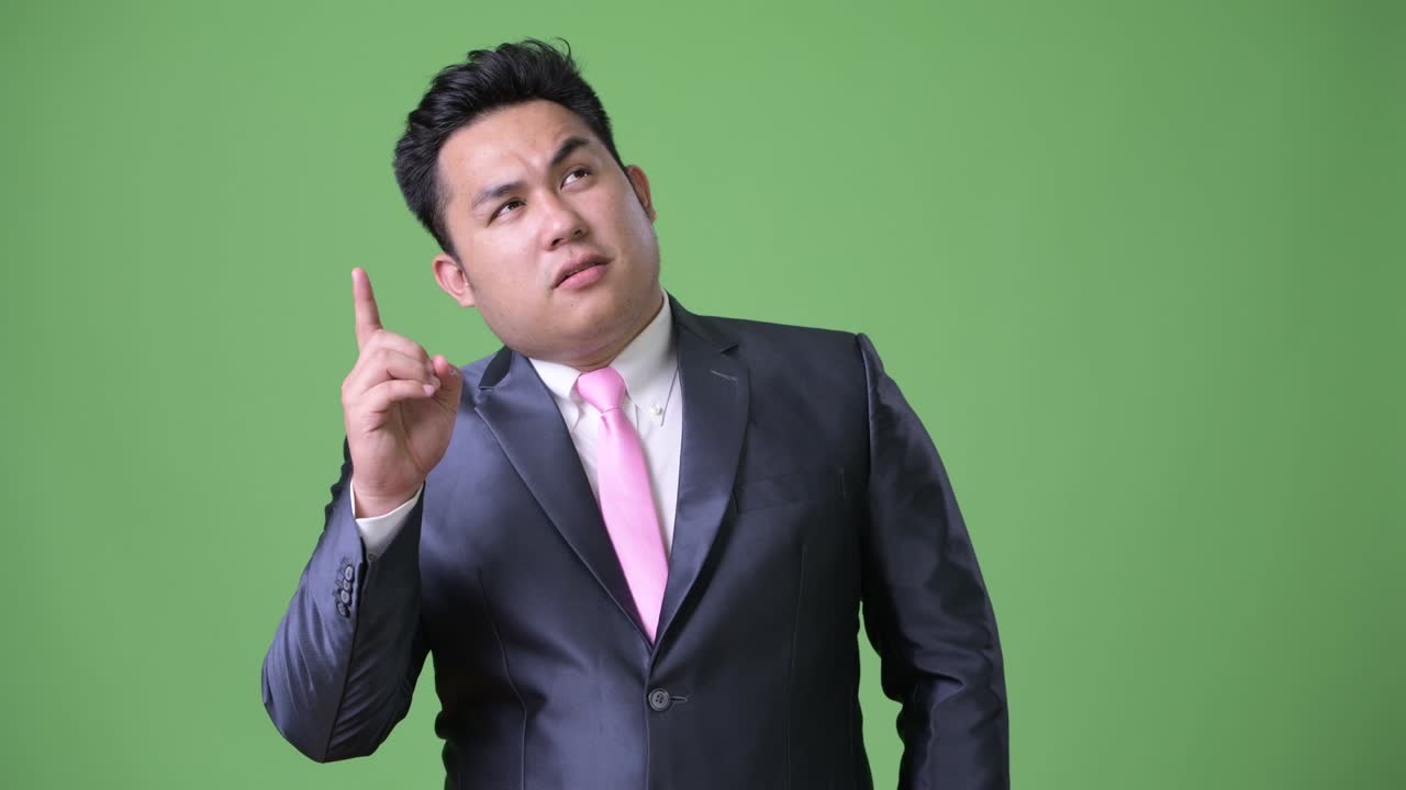 초록색 배경에 젊은 잘생긴 과체중 아시아 사업가