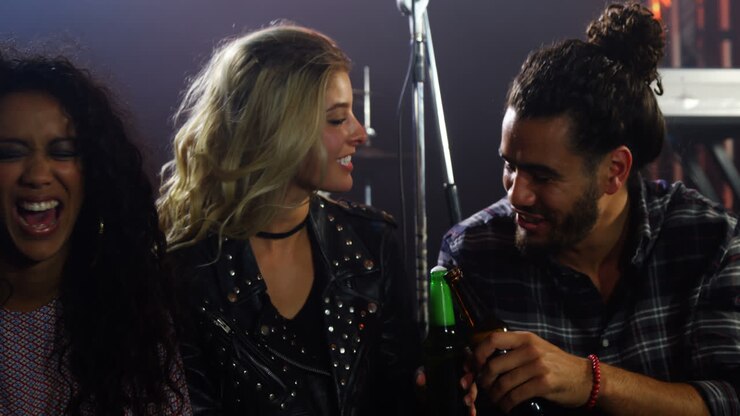 Gruppo di amici che brindano con bottiglie di birra a un concerto 4K.