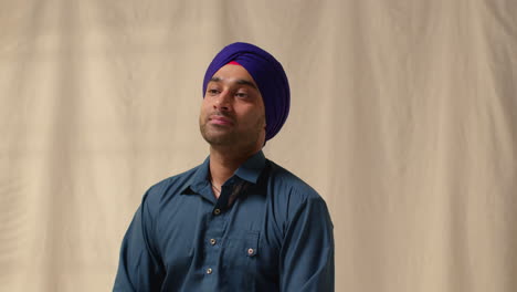 fotografía de estudio de dos hombres sikh usando aguja salai al ponerse el turbante contra un fondo plano