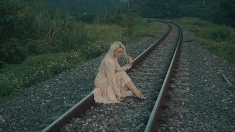 woman in a pink lace dress on train tracks