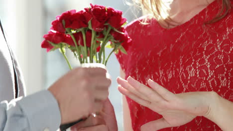 hombre ofreciendo flores y anillo de compromiso