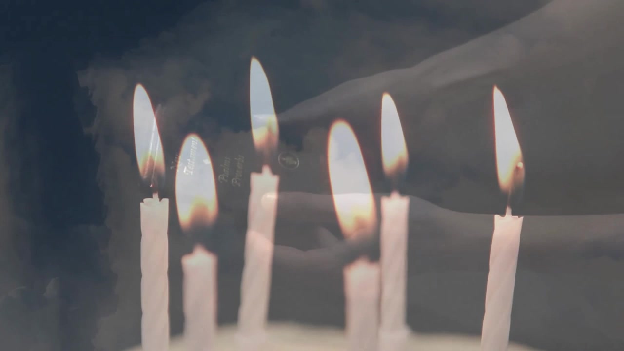 Animazione di candele accese sopra mani che tengono un libro e un cielo con nuvole.