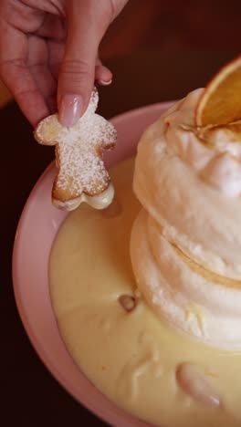 hand dipping a cookie into a delicious fluffy pancake dessert with custard sauce