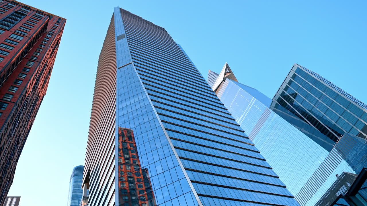 Glass skyscraper reflecting city life in Manhattan skyline. A modern glass skyscraper reflecting nearby architecture and the clear blue sky in Manhattan, New York City