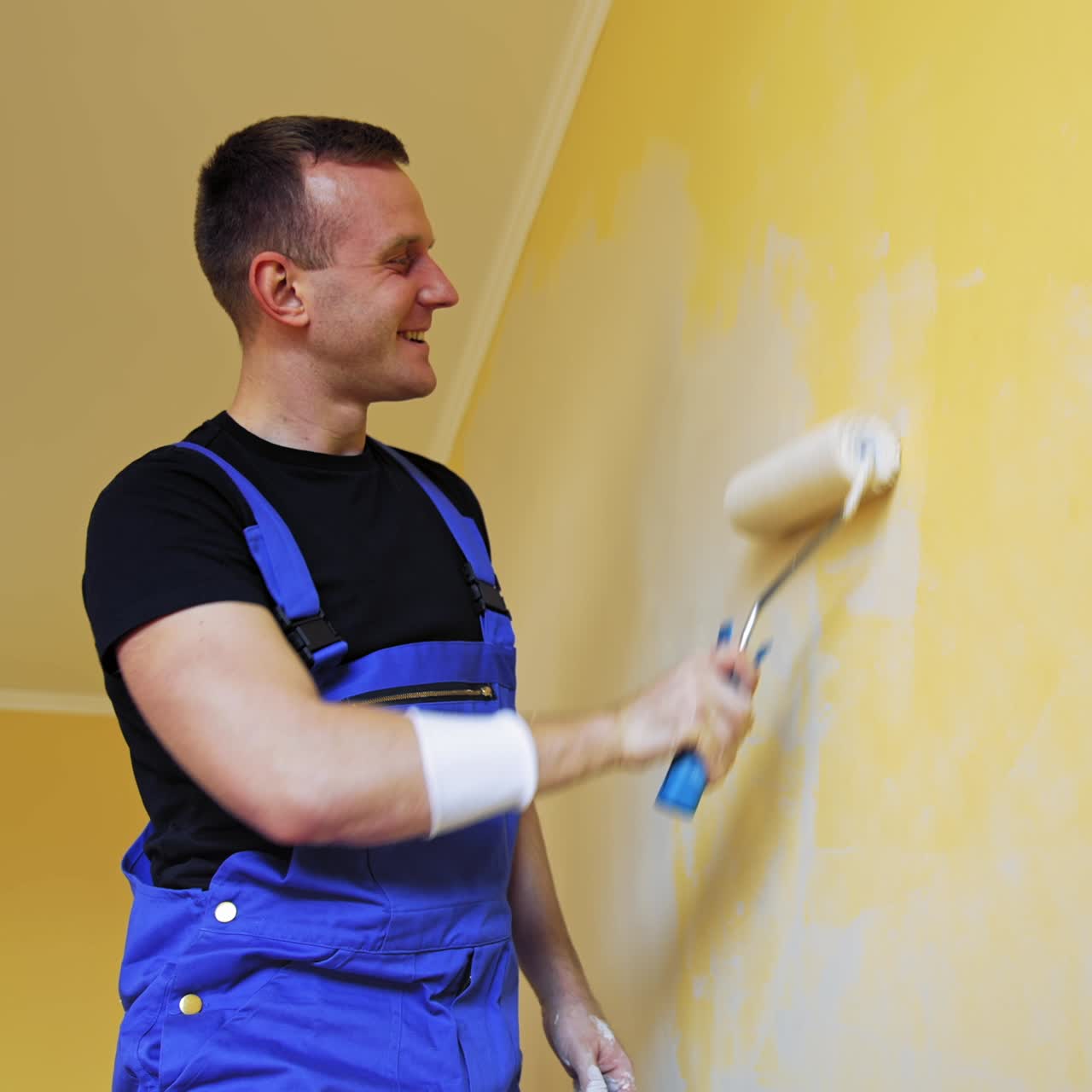 Man singing in paint brush. Cheerful man with rollers for painting the walls singing