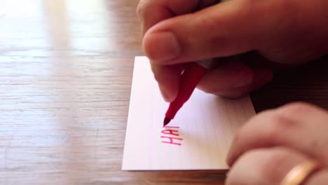 close up footage as male hands write a note using permanent marker pen on a small card of paper