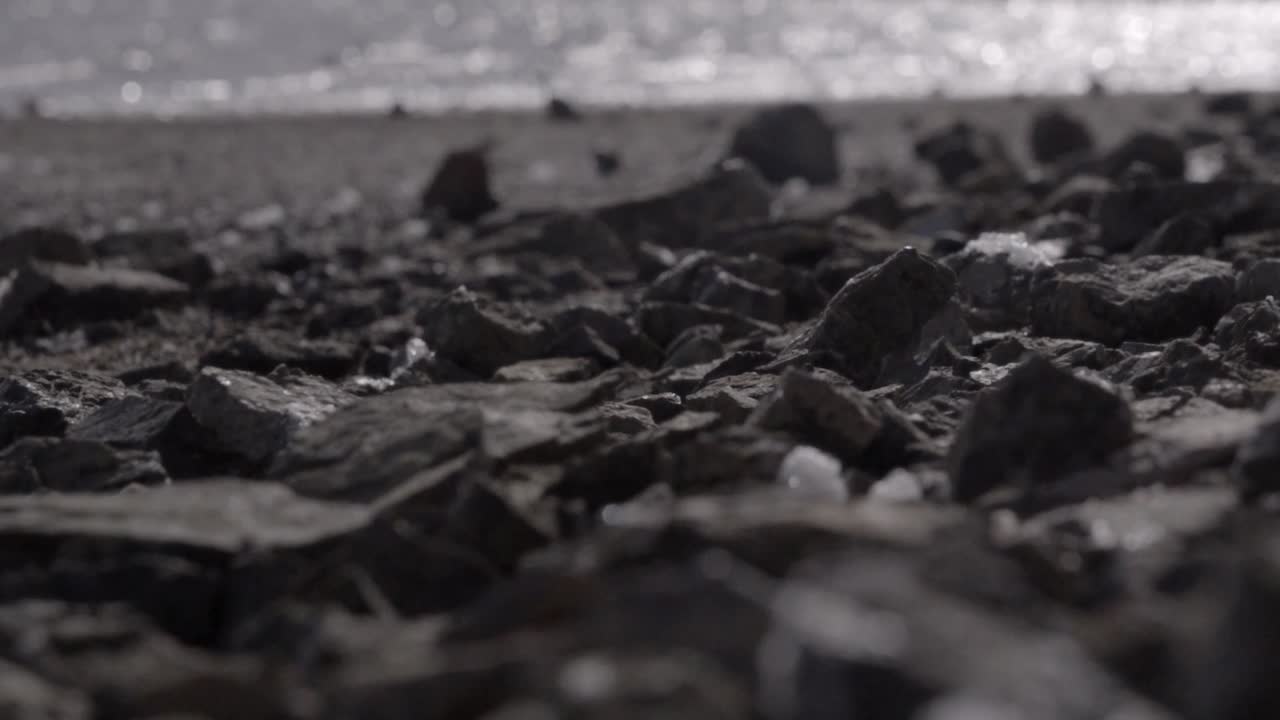 바위가 많은 해안선의 낮은 각도의 추상 샷, 날카롭고 고르지 않은 표면에 하얀 바다 거품을 부는 강한 바람이 조각을 걸러내고 찢어내고, 큐라소