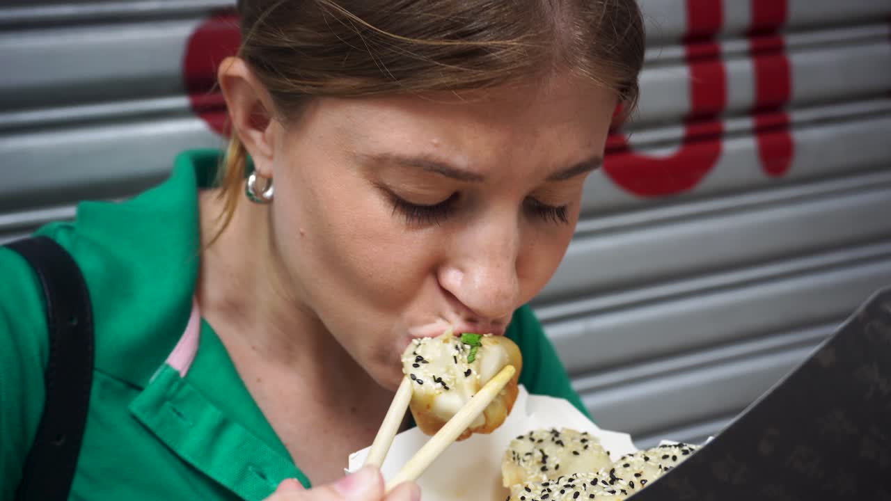 Tourists Eating Xiao long bao dumplings With Chopsticks In Street In Mong kok