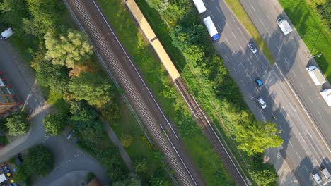 Great-aerial-top-view-flight-Yellow-suburban-train-S-Bahn-on-tracks,-Berlin-Marzahn-summer-2023