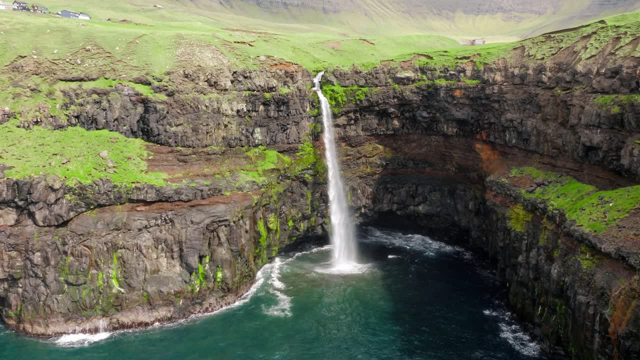 una impresionante cascada desemboca en el mar cerca de gasadalur, faroe, en medio de acantilados verdes
