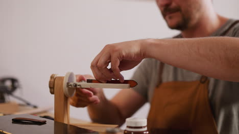 Artisan-puts-leather-into-clamp-and-opens-bottle-in-shop