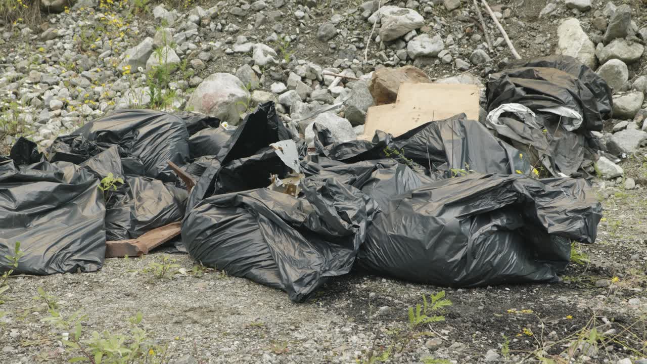 Cinematic angle of beat up garbage bags left out in the wilderness