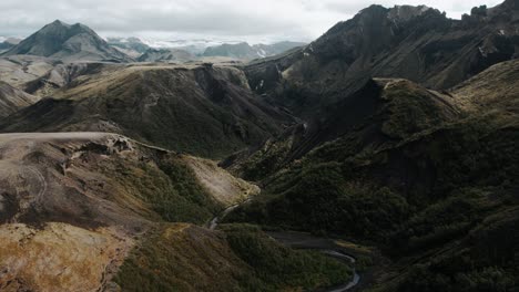 Aerial-thor-valley-glacial-river-in-grassy-mountain-ranges,-famous-icelandic-national-park-landmark-landscape