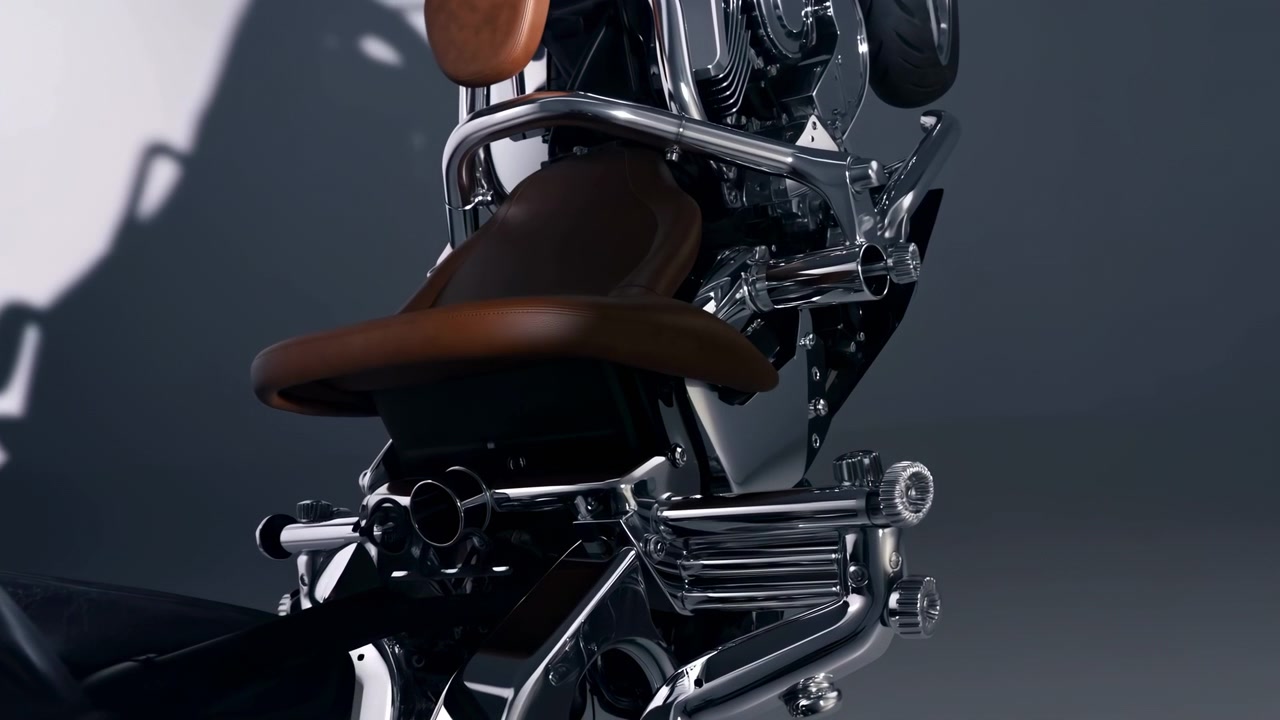 Dettaglio posteriore di una moto custom con sella singola in pelle marrone, illuminata da studio.