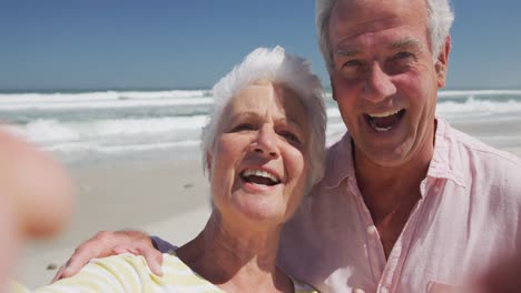 retrato de una feliz pareja caucásica soplando besos mirando a la cámara en la playa