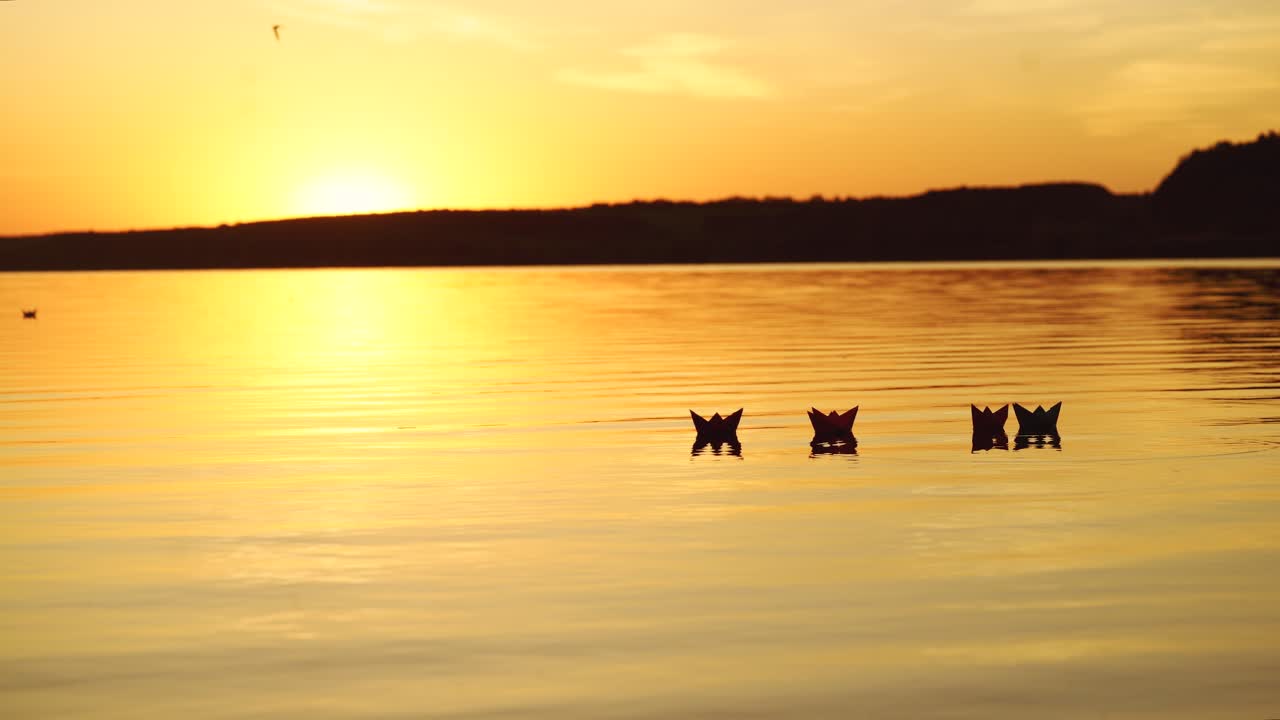 Floating paper boats on the water at sunset. Paper boat. Origami.