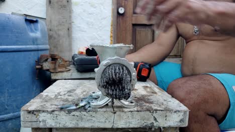 hands man grinds small fishes bait to chum use drill to speed up manual work