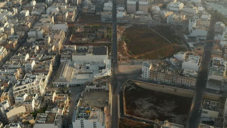 Road-going-through-City-on-Malta-Island-with-little-car-traffic-and-with-Beige-Brown-Buildings,-Aerial-Drone-forward-dolly