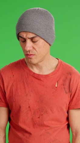 sad homeless man looking at camera on green screen background