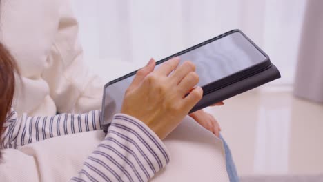 mujer asiática usando tableta jugando juegos y redes sociales o charlando con sus amigas.