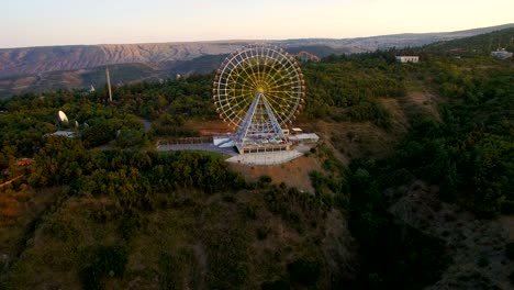 large ferris wheel on  mountain at sunset. video editing aerial view