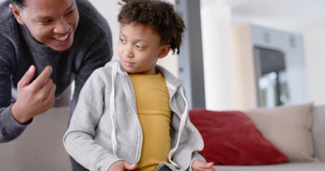 African American father and daughter, child tapping tablet drawing father leaning in, guiding taps