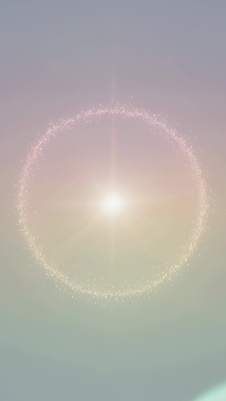 Vídeo vertical: Efeito flare de lente aparecendo, anel de partículas brilhando com luz central em meio a um gradiente pastel