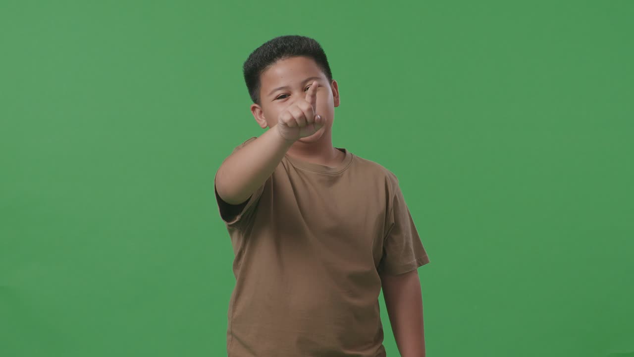 분노 한 아시아 소년 이 스튜디오 에서 녹색 스크린 에 서 있는 동안 비난 하고 있다