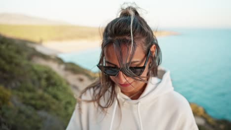 Toma-En-Cámara-Lenta-Del-Cabello-De-Una-Mujer-Soplando-Sobre-Su-Rostro-Durante-La-Puesta-De-Sol-En-El-Océano