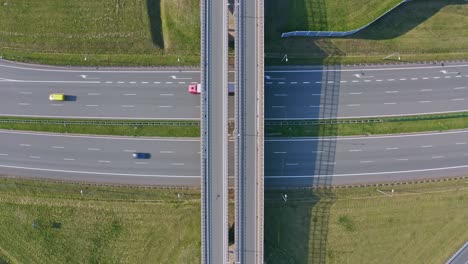 traffic flow on highway with overpass, green landscape surrounds asphalt