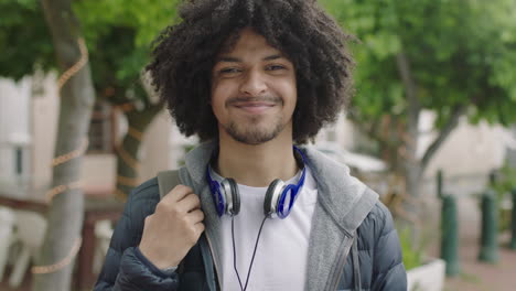 portrait of young confident mixed race student man smiling happy looking at camera commuting in city enjoying urban lifestyle cool afro hairstyle