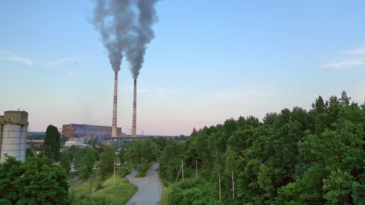 Cityscape background with two big pipes with smoke from factory. Dark smoke comes from industrial pipes near green trees. Pollution of the environment.
